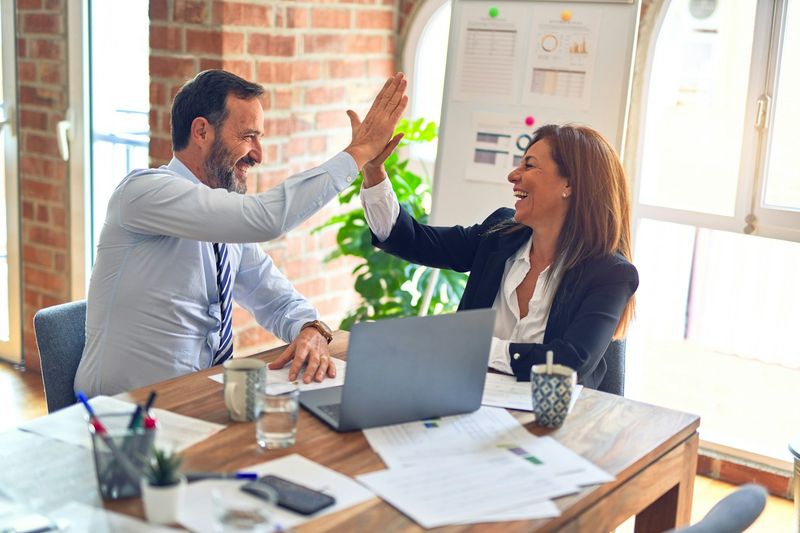Two colleagues celebrating a win with a high five