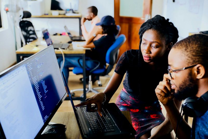 Young start-up team collaborating around laptops
